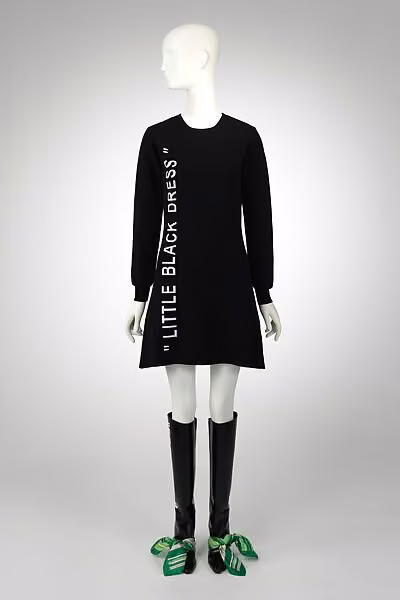 Black knitted dress printed with the words LITTLE BLACK DRESS, displayed with tall tied boots.