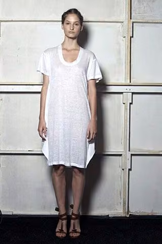 Model in a simple white short-sleeved knee-length dress.