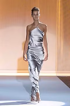 Runway model in a long silver satin-like gown with a halter neckline.