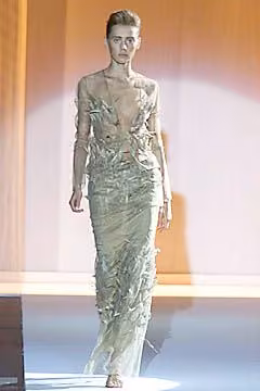Runway model in a pale embroidered sheer long-sleeved gown.