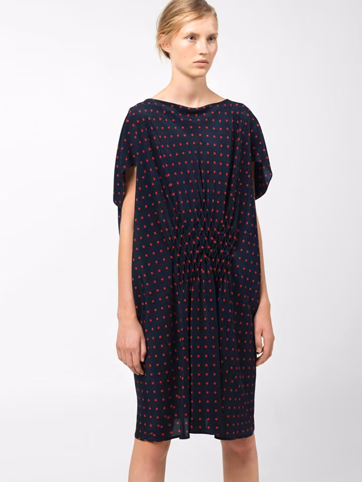 Model in a loose dark dotted dress with slit sleeves.