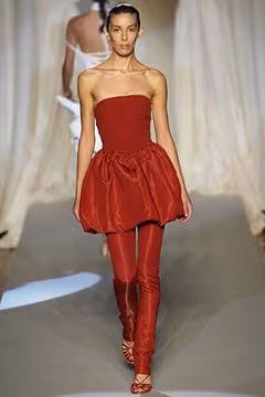 Runway model in a strapless red bubble dress over red leggings.