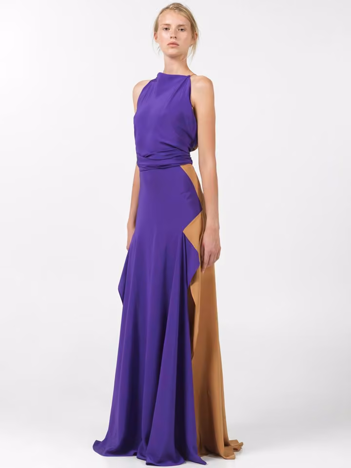 Model in a draped purple gown with an asymmetric ochre panel.