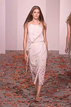 Runway model in a pale sleeveless dress with a patterned lower section.
