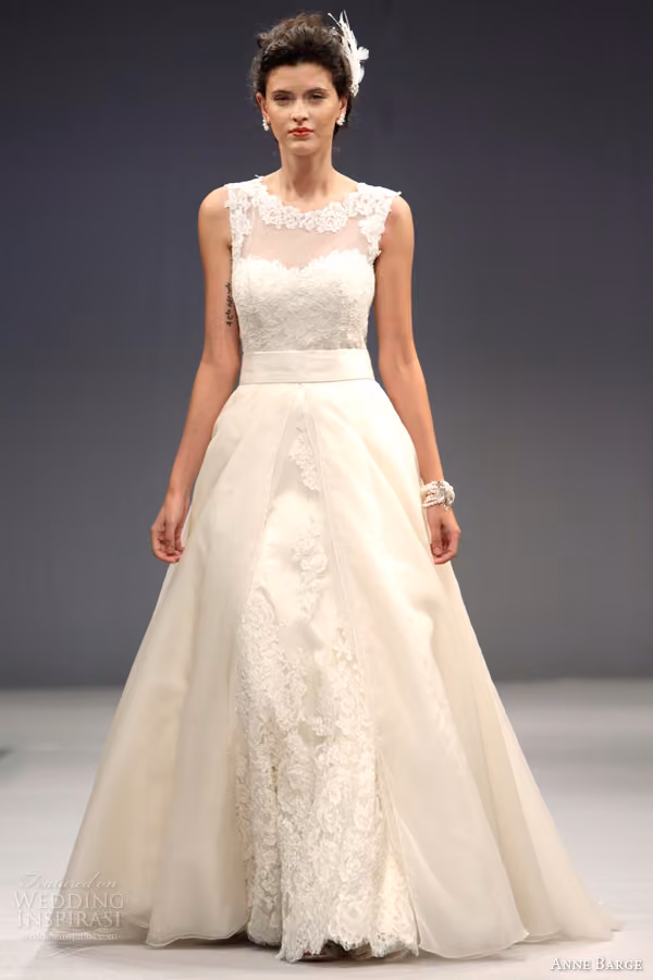 Runway model in the Victoire lace gown with sheer neckline and detachable overskirt.