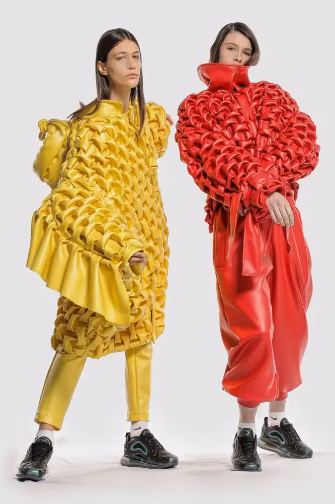Yellow sculpted ensemble, left model — Romina Cardillo, Nous Etudions x Nike Sportswear capsule, presented at Designer BA