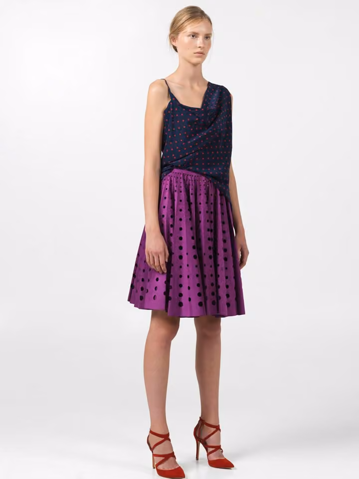 Model in a sleeveless dark-and-purple dotted dress.